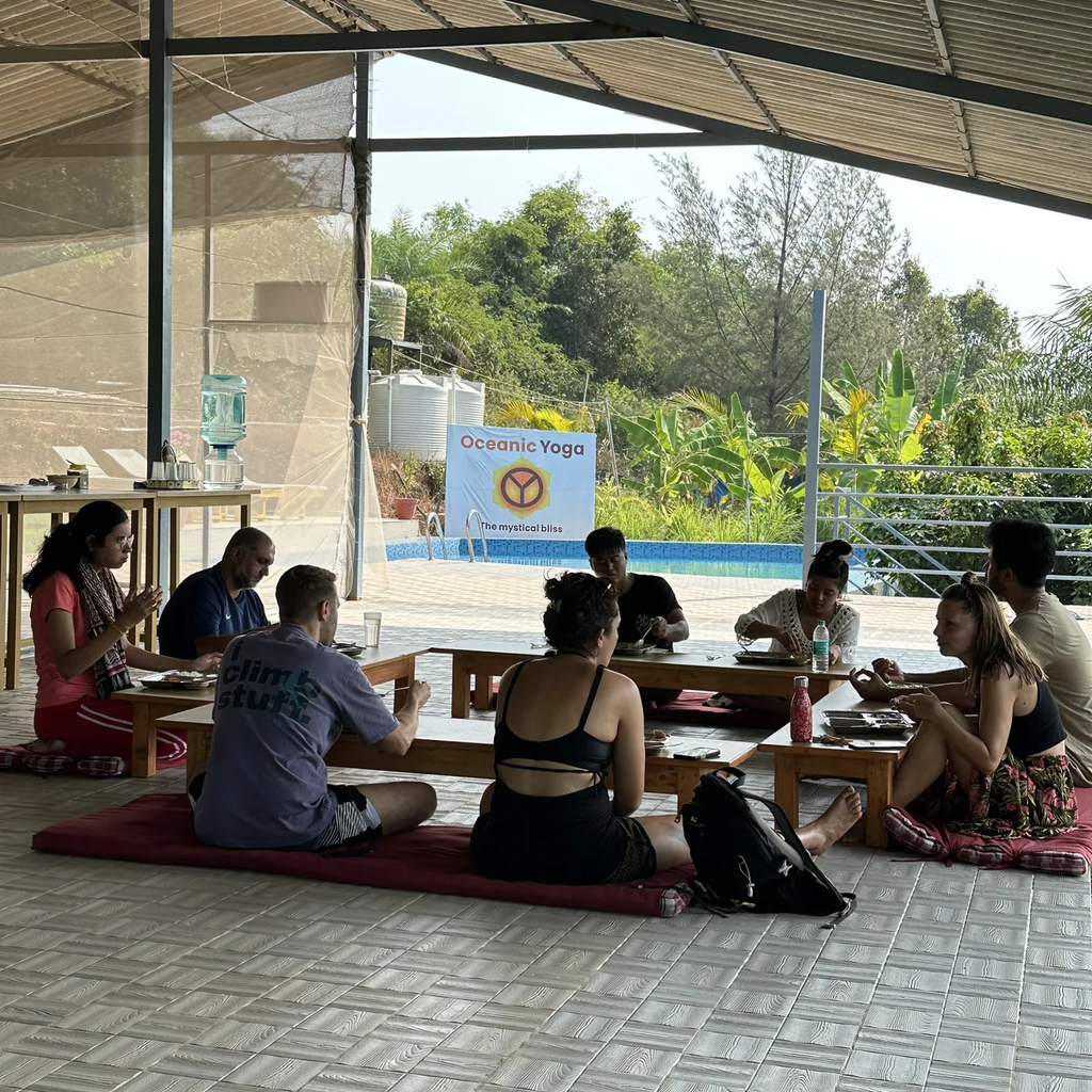 Students sharing sattvic meal and community discussion during trauma-informed YTT at Oceanic Yoga Morjim
