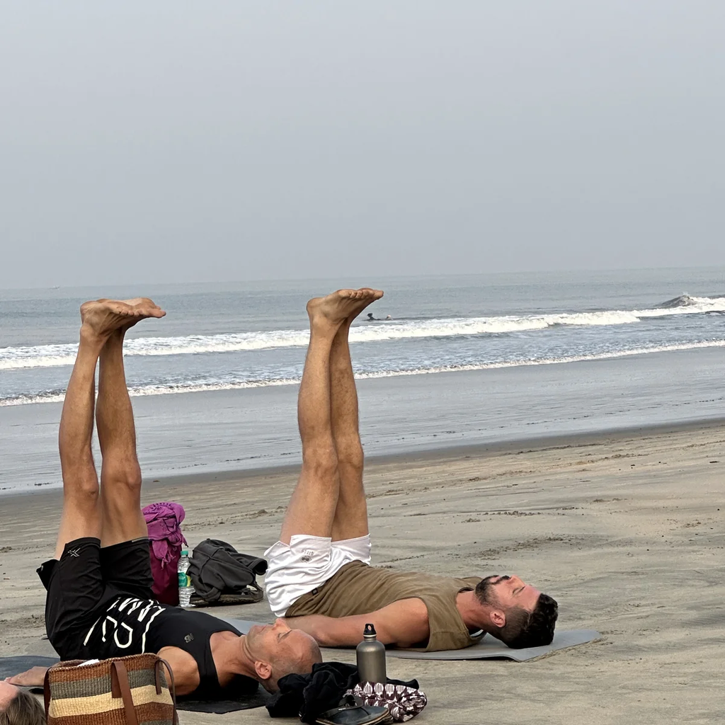 Students practicing restorative yoga inversion on Morjim beach in Goa as part of Ayurvedic lifestyle